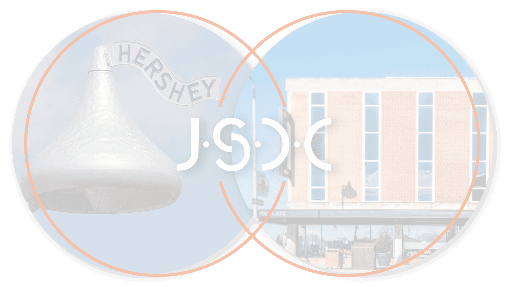 View through binoculars showing a large Hershey's Kiss sculpture and a brick building under a clear blue sky.