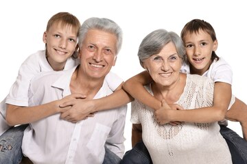 Happy grandparents and their two grandchildren on a white background.