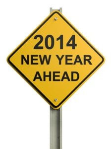 A yellow diamond-shaped road sign on a metal post that reads "2014 NEW YEAR AHEAD" in bold black capital letters